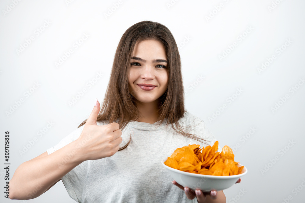 young attractive woman standing with plate of spicy potatoe chips showing like sign on isolated white background dietology and nutrition young attractive woman standing with plate of spicy potatoe chips showing like sign on isolated white background dietology and nutrition