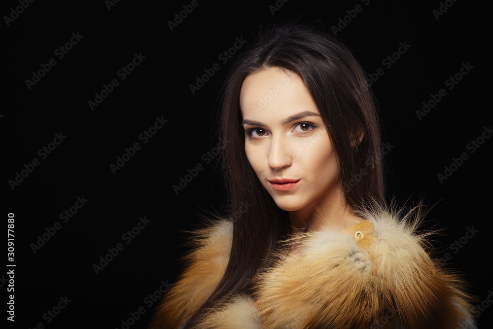 Beautiful happy girl in fur coat over black background
