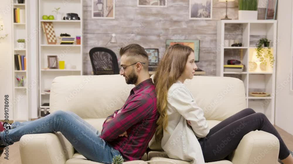 Couple sitting back to back on the couch with arms crossed Couple sitting back to back on the couch with arms crossed