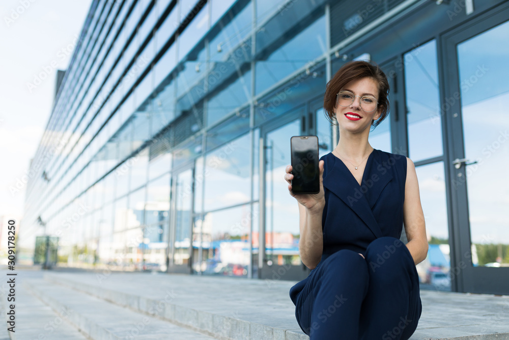 Caucasian woman in office clothes waits colleague near the office building Caucasian woman in office clothes waits colleague near the office building