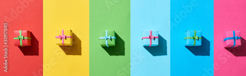 top view of multicolored gift boxes on rainbow background, panoramic shot photo