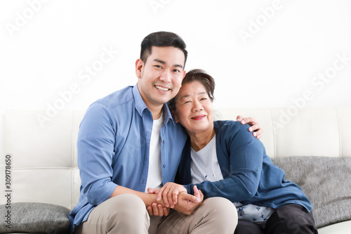 Asian young man and senior woman using laptop computer in living room concept Son teach mother use computer laptop
