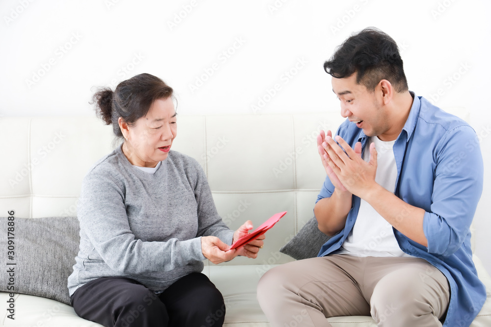 Chinese New year concept : Asian Senior mother give Red envelope to her son for gift money Chinese New year concept : Asian Senior mother give Red envelope to her son for gift money
