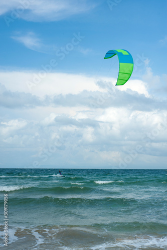 Kite surf ride his hydrofoil kite through surfing waves on sea. Kitesurfers ride kites on Black Sea at sandy Beach In Bulgaria, Sozopol on sunny day at sunset on blue sky and clouds background.