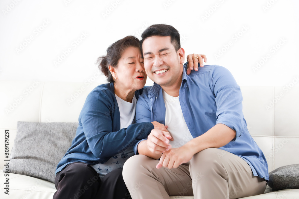 Asian senior mother in blue shirt kiss her son happy and smile face in living room Asian senior mother in blue shirt kiss her son happy and smile face in living room