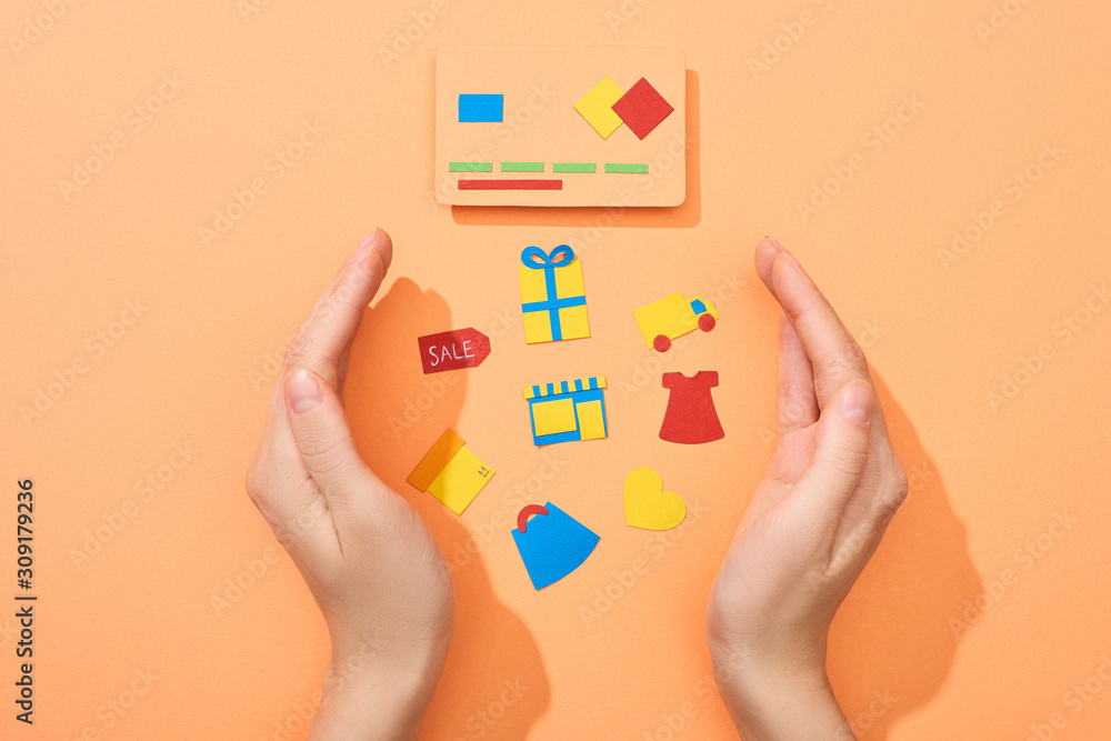 cropped view of female hands around icons near credit card template on peach background cropped view of female hands around icons near credit card template on peach background