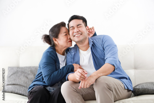 Asian senior mother in blue shirt kiss her son happy and smile face in living room