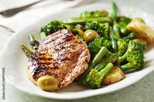 Grilled Turkey Breast with oven baked potatoes and broccoli. Bright  wooden background. Close up. 