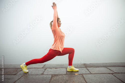 Sporty lady doing low lunge pose or anjaneyasana