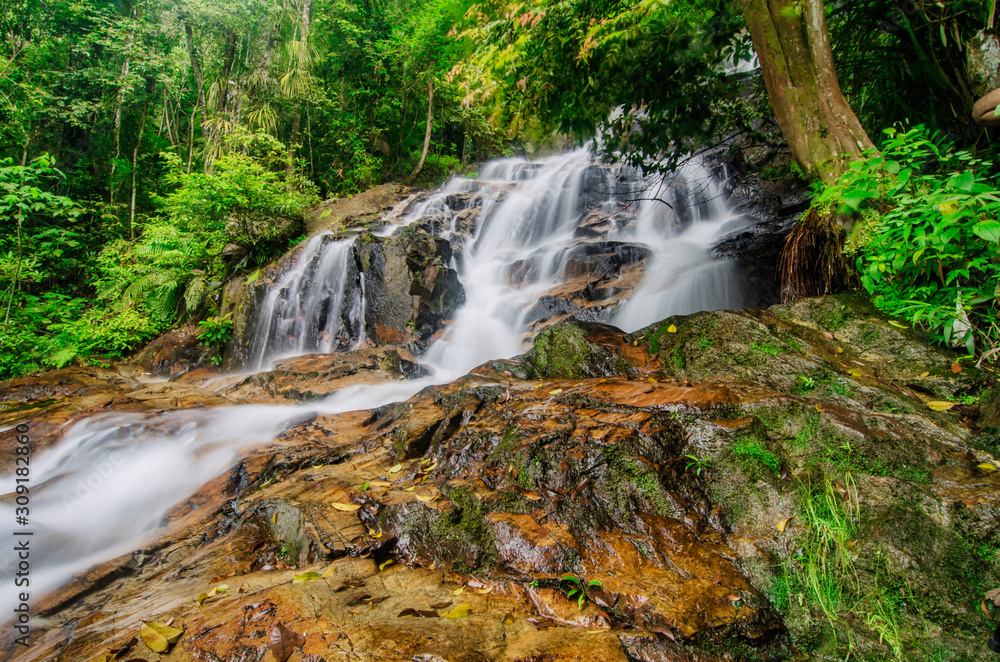Beautiful tropical waterfall in lush surrounded by green forest.wet rock and moss.selective focus shot. Beautiful tropical waterfall in lush surrounded by green forest.wet rock and moss.selective focus shot.