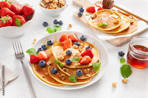 pancakes with blueberry strawberry honey and nuts for breakfast