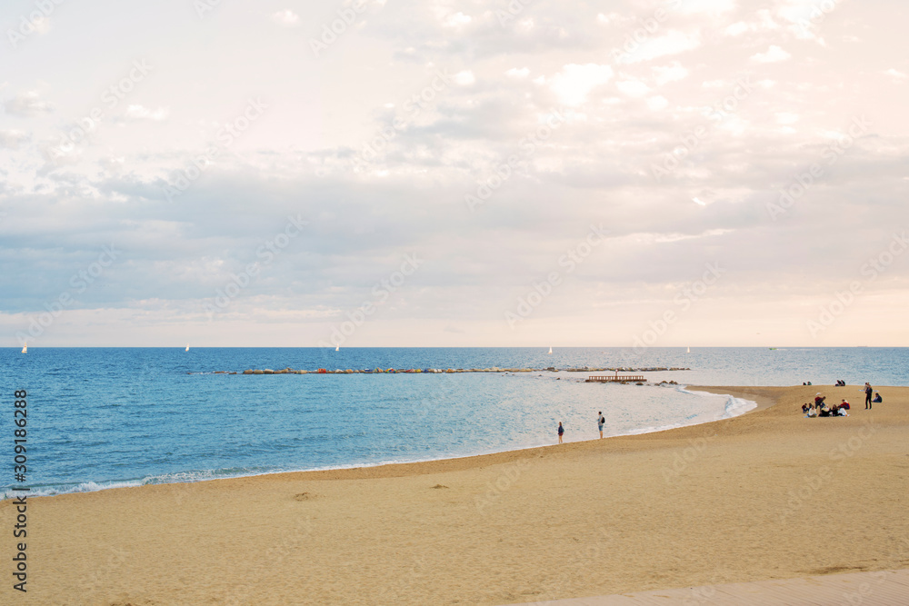 View of Barcelona beach, in the Barceloneta district, overlooking the Mediterranean Sea. The sky is dark and there are many waves.