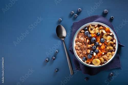 chocolate oatmeal porridge with blueberry, nuts, banana, dried apricot for healthy breakfast. Top view