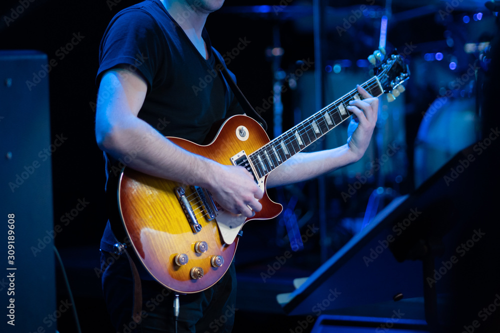 Obraz premium Man playing electric guitar on the stage at the rock concert