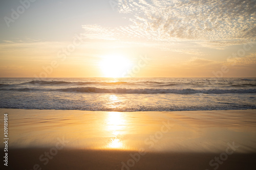 Wide panorama of waves coming in at the Arpoador Devil s beach in Rio de Janeiro  Brazil  at sunrise with the sun reflecting in the water that hits the pristine sand beach