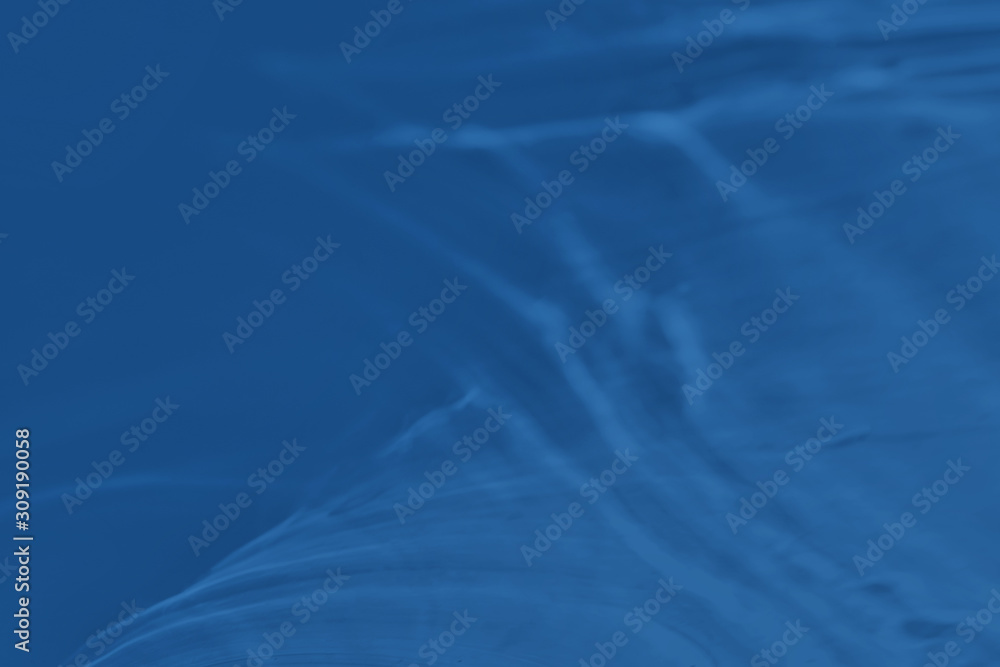 Trendy blue colored low contrast abstract background with light and shadows caustic effect. Light passes through a glass. Water background. 2020 year color trend Trendy blue colored low contrast abstract background with light and shadows caustic effect. Light passes through a glass. Water background. 2020 year color trend