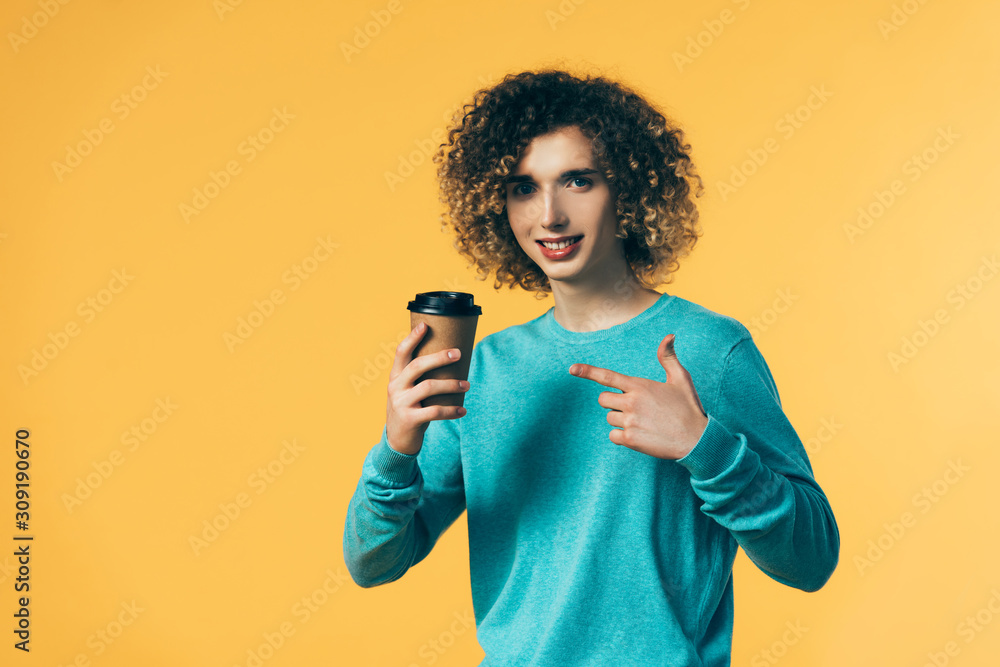 smiling curly teenager pointing at coffee in paper cup isolated on yellow smiling curly teenager pointing at coffee in paper cup isolated on yellow