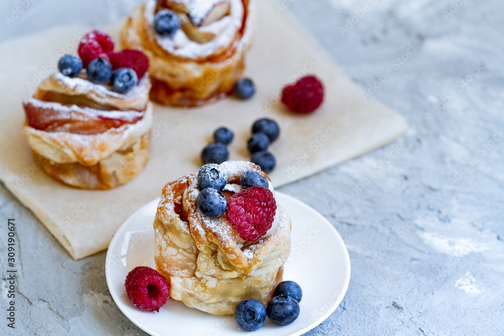 Delicious and beautiful berry rose puff pastries. Classic winter sweet dessert on blue background. French new year dessert. Delicious and beautiful berry rose puff pastries. Classic winter sweet dessert on blue background. French new year dessert.