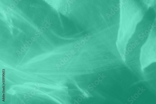 Trendy mint colored abstract background with light and shadows caustic effect. Light passes through a glass. 2020 year color trend. Water background. 