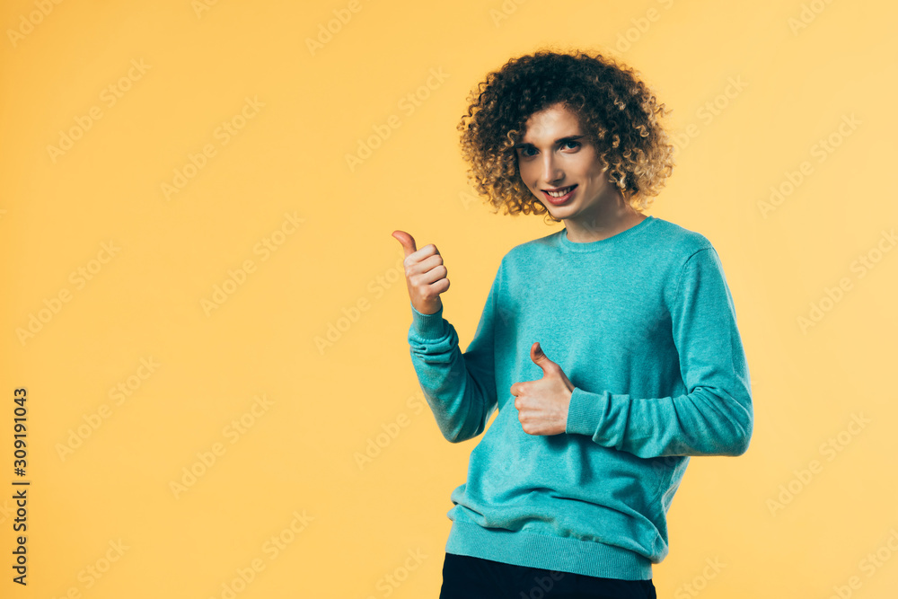 happy curly teenager showing thumbs up isolated on yellow happy curly teenager showing thumbs up isolated on yellow