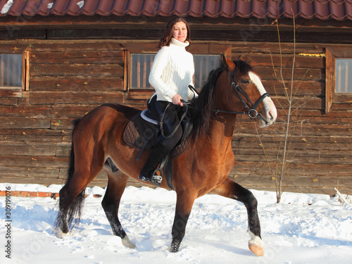 Equestrian country girl riding her horse in winter farm