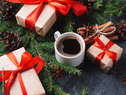 A Cup of coffee on the holiday table and gift boxes Packed in Kraft paper and red ribbon