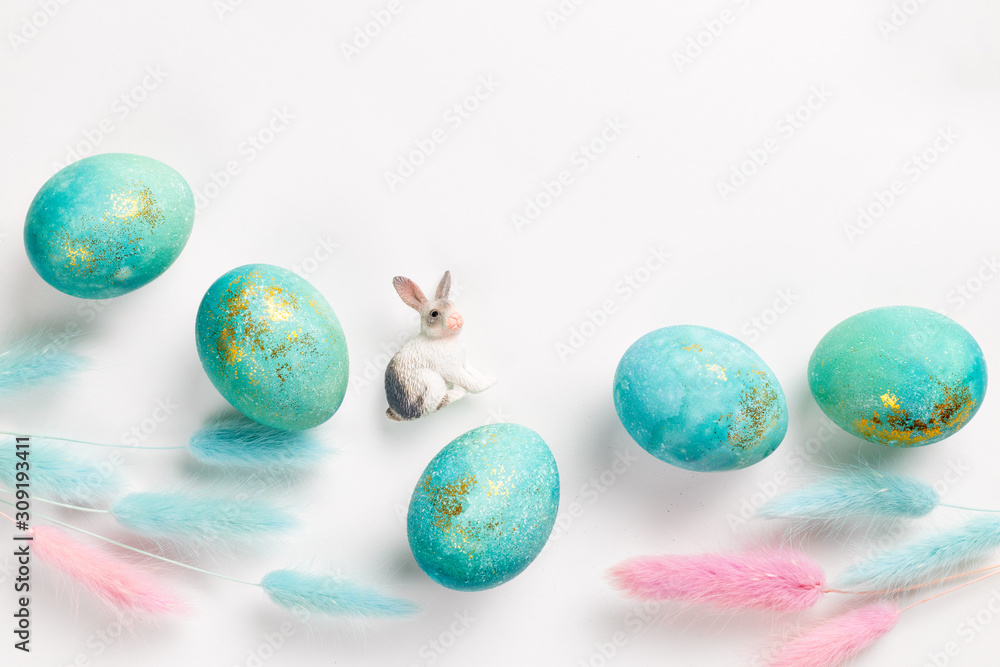 Happy easter card. Stylish minimalistic composition of turquoise with gold easter eggs on a white background. Figurine of a rabbit and delicate spring flowers. Flat lay, top view, copy space Happy easter card. Stylish minimalistic composition of turquoise with gold easter eggs on a white background. Figurine of a rabbit and delicate spring flowers. Flat lay, top view, copy space