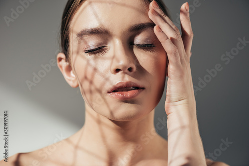 Obraz na plátně portrait of tender naked woman with closed eyes and shadows on face on grey