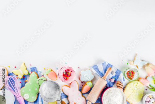 Sweet Easter baking cooking background with traditional Easter bunny and egg cookies  sugar sprinkles  ingredients  utensils. White table background copy space layout