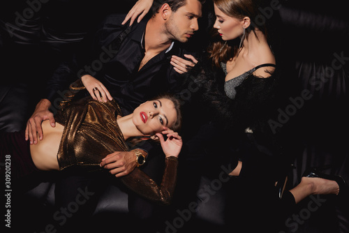 top view of attractive women lying and hugging handsome man isolated on black