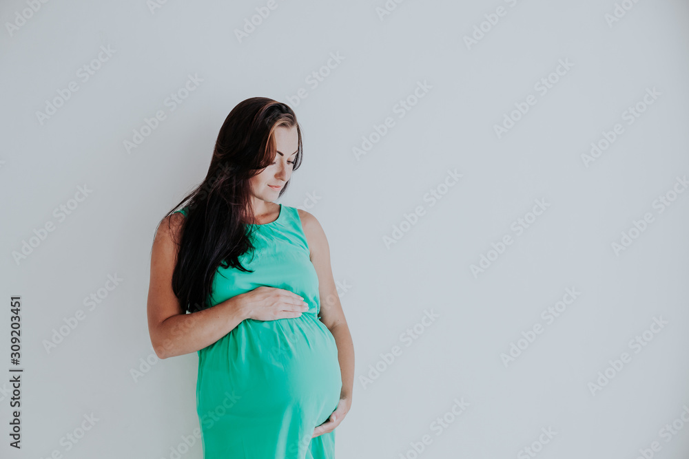 a pregnant woman is standing at the wall next to the window a pregnant woman is standing at the wall next to the window