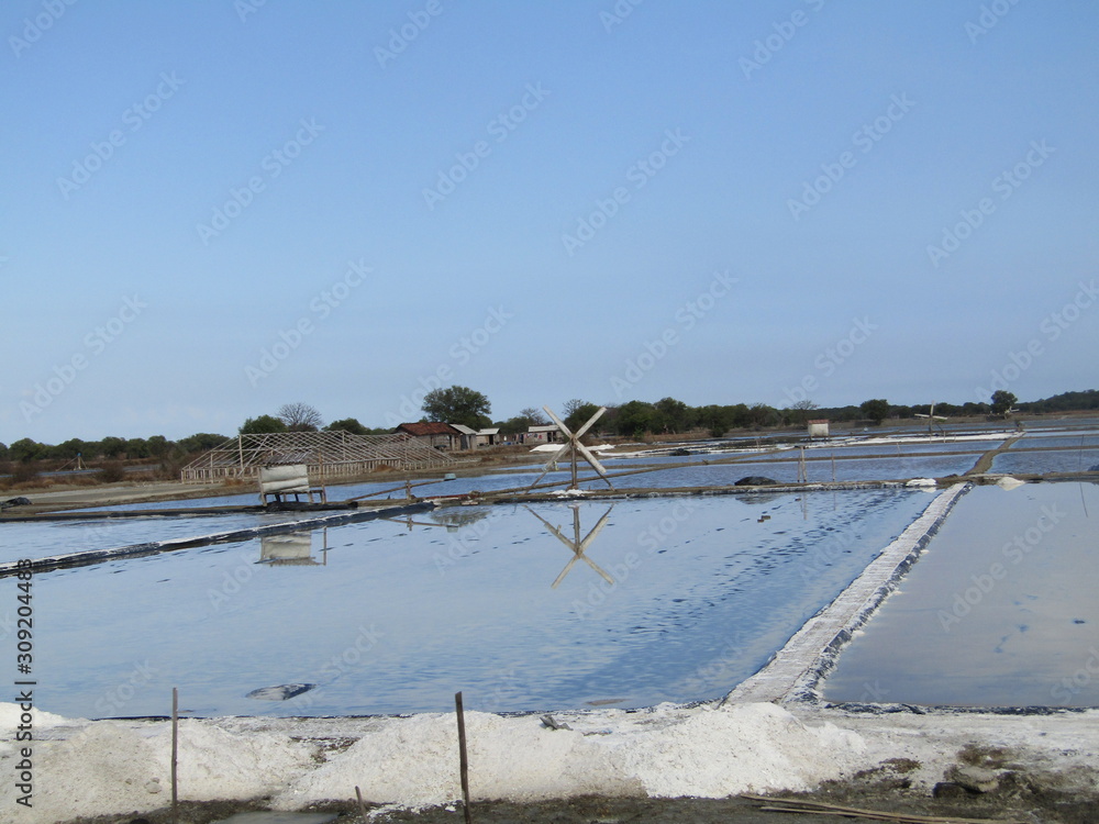 A view of a natural salt evaporation pond or tambak garam in village of Sidoarjo region. Traditional home industry with artificial shallow ponds designed to produce from sea water or water brines.