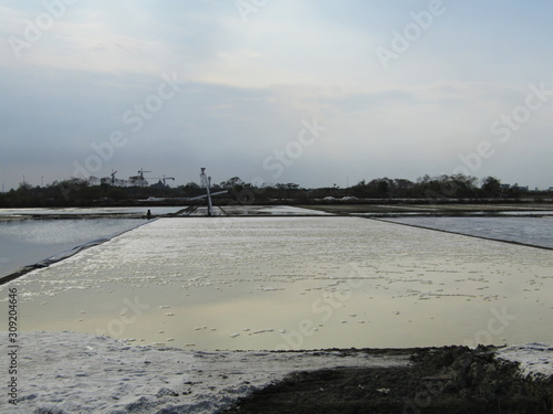 A view of a natural salt evaporation pond or tambak garam in village of Sidoarjo region. Traditional home industry with artificial shallow ponds designed to produce from sea water or water brines. photo