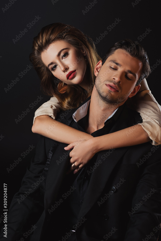 attractive woman hugging handsome man in suit isolated on black attractive woman hugging handsome man in suit isolated on black
