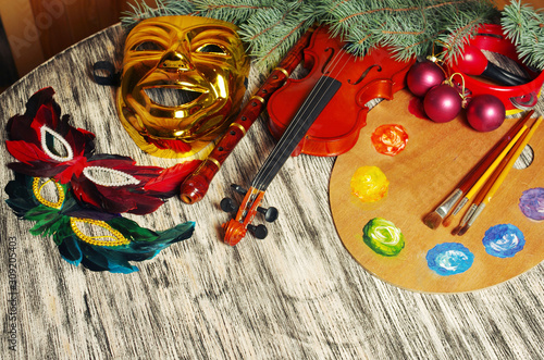 Carnival still life. Carnival masks, violin, flute, maracas, tambourine on a decorated table.
