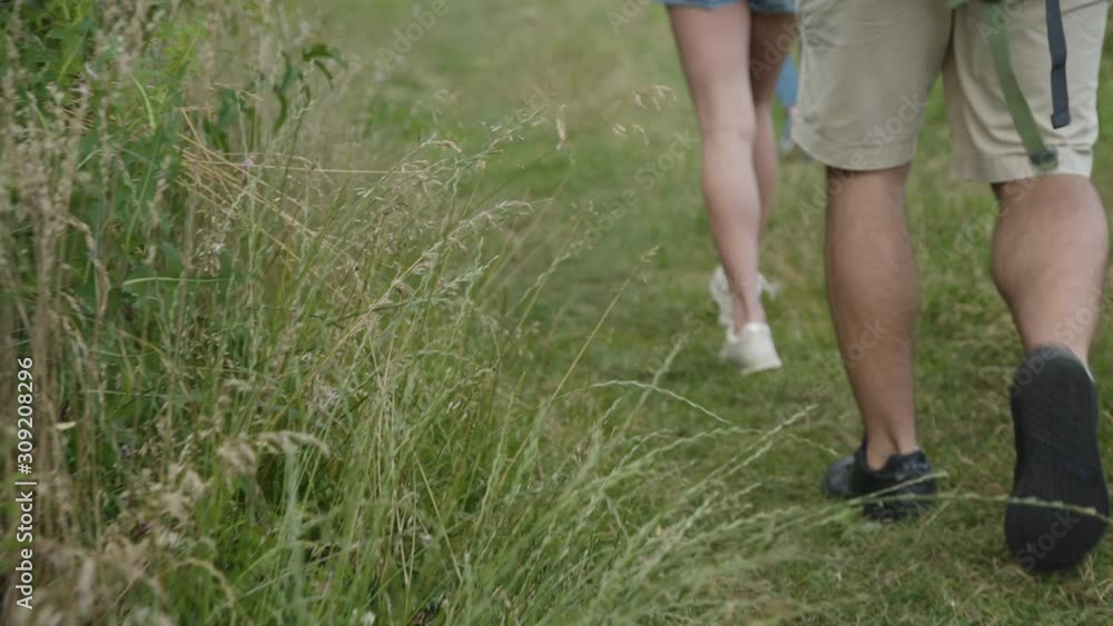 Unrecognizable male and female legs walk on wild nature path Unrecognizable male and female legs walk on wild nature path