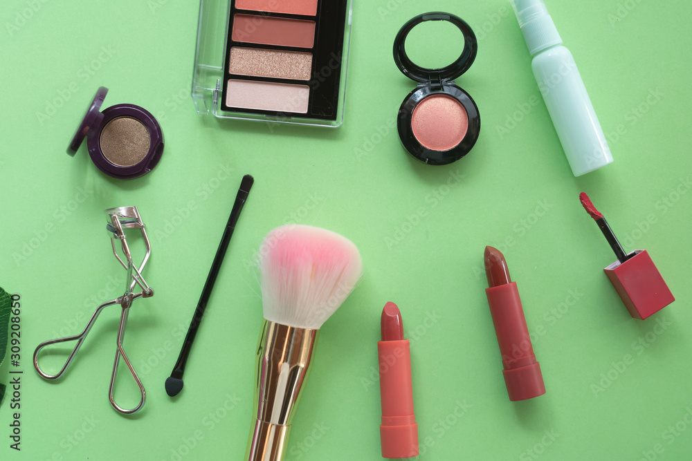 A collection of make up and cosmetic products arranged on a pastel green background.beauty concept. A collection of make up and cosmetic products arranged on a pastel green background.beauty concept.