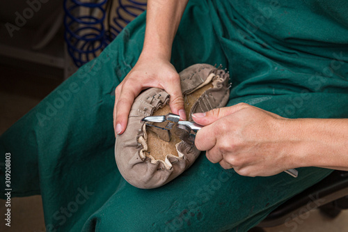 Foto close up of orthopedic shoemaker covering a wooden last with leather