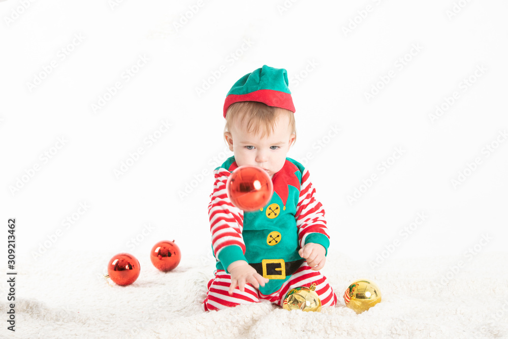 Baby disguised elf with hat removed from head rolled from Christmas balls Baby disguised elf with hat removed from head rolled from Christmas balls