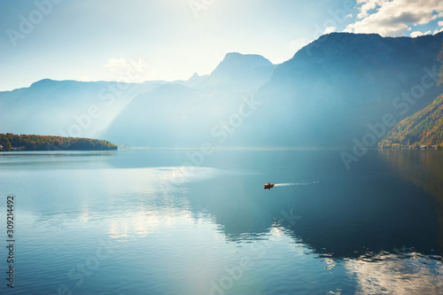 Boat floating on the Hallstatter lake in Alps mountains, Austria. Beautiful autumn landscape