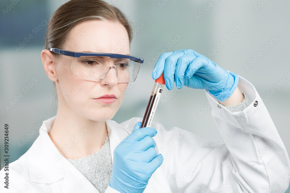 Female scientist with medical gloves and safety glasses is handling a blood probe in a test tube Female scientist with medical gloves and safety glasses is handling a blood probe in a test tube