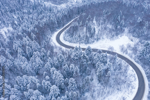Aerial view of winter road and forest with snow covered trees, top view