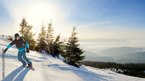 Young Snowboarder Riding Red Snowboard in Mountains at Sunny Day. Snowboarding and Winter Sports