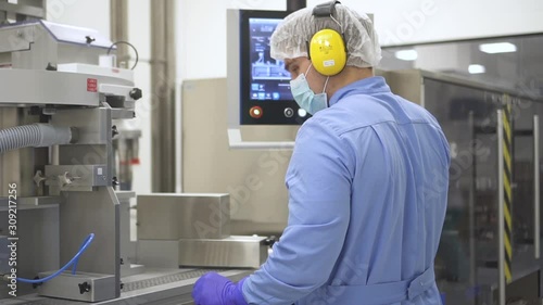 Wallpaper Mural American man engineer working with computer and equipment in modern pharmaceutical company. Back view of employee looks at screen and controls metal facilities in pharma chemical factory. Concept Torontodigital.ca