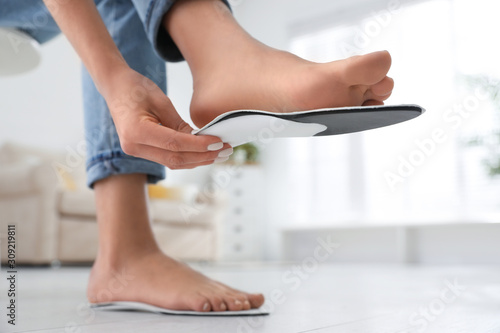 Woman fitting orthopedic insole at home, closeup photo