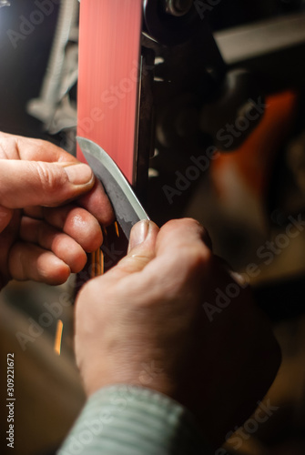 locksmith hands sharpen the workpiece for a knife