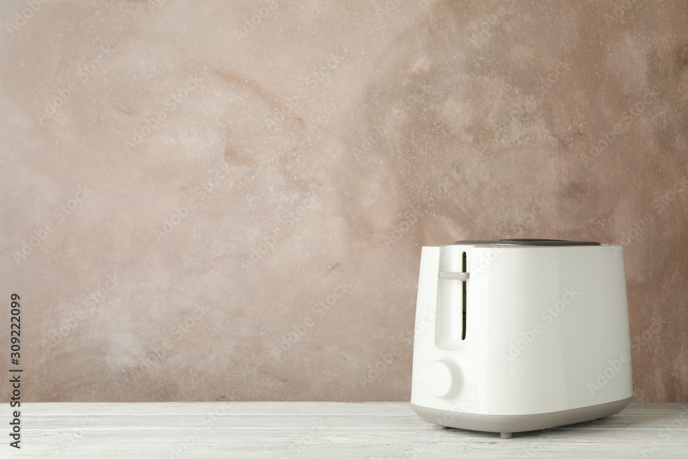 Toaster on wooden table against brown background, space for text Toaster on wooden table against brown background, space for text