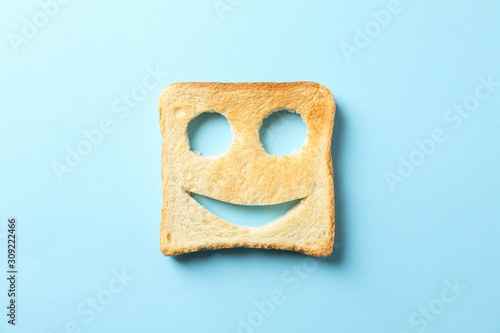 Tasty bread toast with happy face on blue background, top view