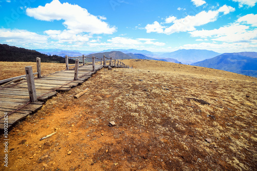 long wooden walkway with golden vast plain of Yak Meadow in Jade Dragon Snow Mountain area in Lijiang, Yunnan, China
