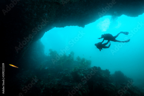 A couple of scuba divers exploring the an underwater arch.